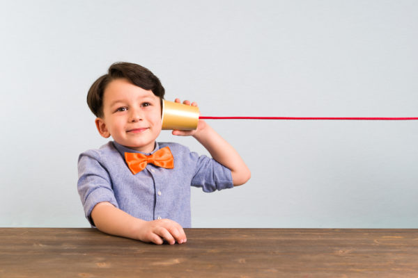 The child is using paper cup as a telephone