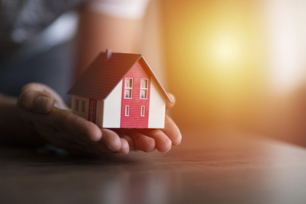 Business man hand hold the house model saving small house